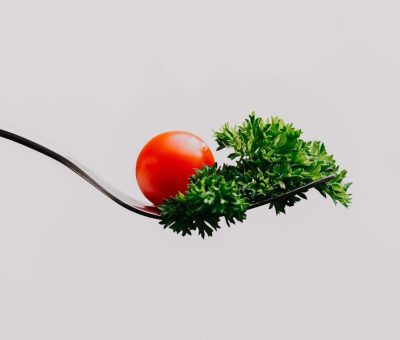 Minimalist close-up of a cherry tomato and parsley on a fork. Perfect for food design.